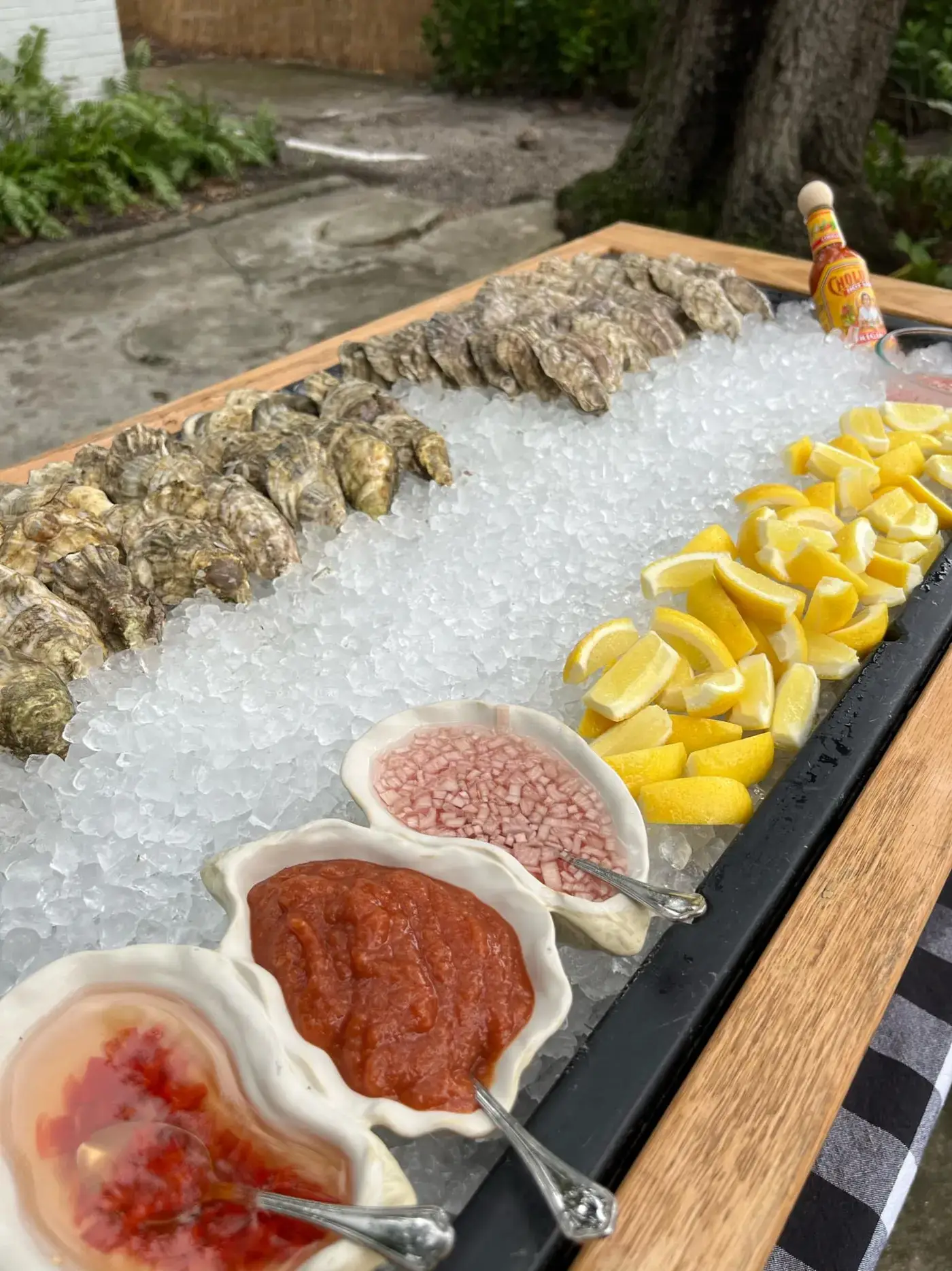 Raw bar board of oysters on ice with lemons and sauces at a Lazy Oyster event